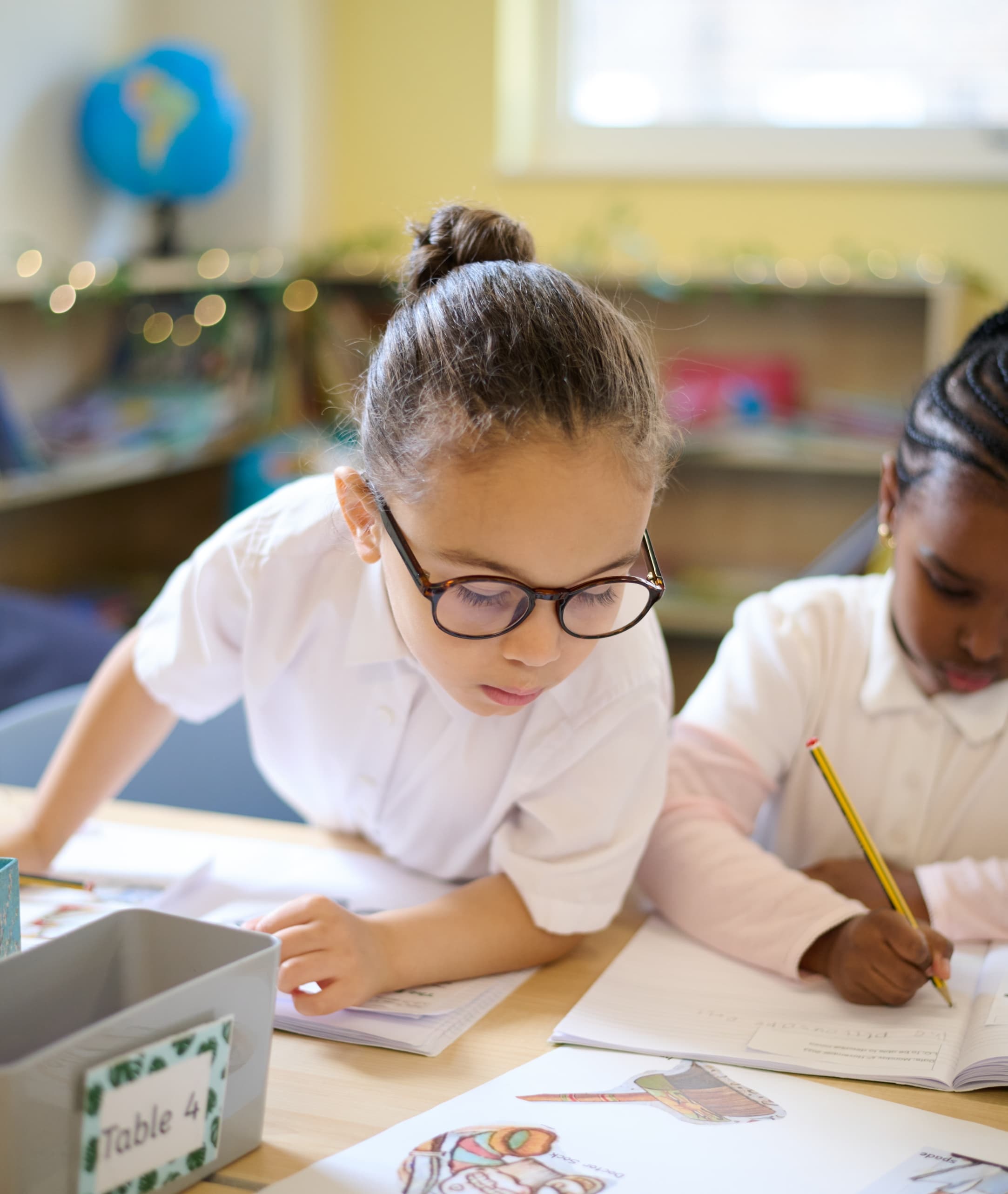 Children working in their excerise books whilst looking at a reference book